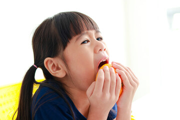 An Asian little girl is eating a very sour orange. food nutrition concept for kids