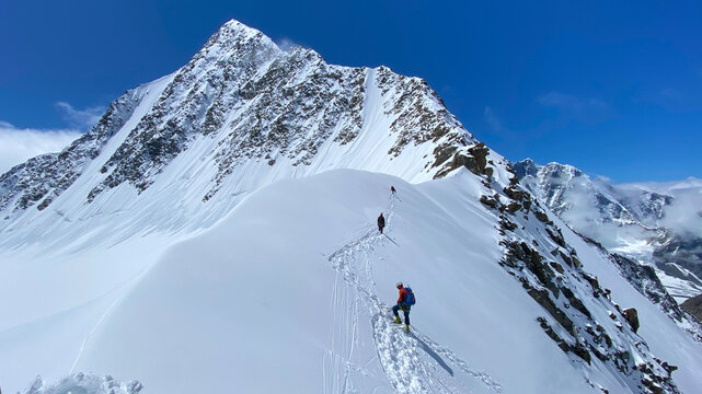 Three climbers are walking on a snow-covered mountain slope. Climbing Belukha. Altai Mountains. - Powered by Adobe