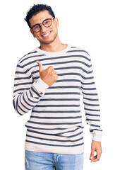 Hispanic handsome young man wearing casual clothes and glasses doing happy thumbs up gesture with hand. approving expression looking at the camera showing success.