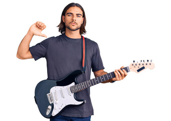 Young handsome man playing electric guitar with angry face, negative sign showing dislike with...