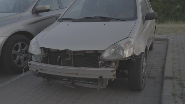 Crashed old car with broken bumper on city parking lot. Concept of missing part and vehicle accident consequences. Transport to be repaired