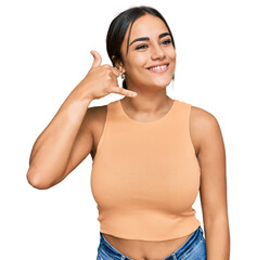Naklejka premium Young brunette woman wearing casual clothes smiling doing phone gesture with hand and fingers like talking on the telephone. communicating concepts.