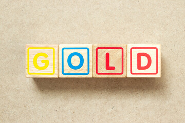 Wooden alphabet letter block in word gold on wood background