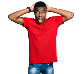 Young african american man wearing casual red t shirt crazy and scared with hands on head, afraid and surprised of shock with open mouth
