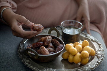 Muslim woman picking dried dates in metal bowl and fresh yellow date palm in tray, healthy fruit, Dates are an important traditional Iftar food for Muslims