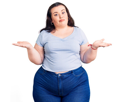 Young plus size woman wearing casual clothes clueless and confused expression with arms and hands raised. doubt concept.