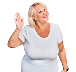 Middle age blonde woman wearing casual white t shirt waiving saying hello happy and smiling, friendly welcome gesture © Krakenimages.com