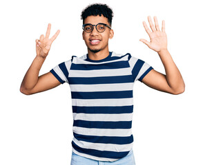 Naklejka premium Young african american man wearing casual clothes and glasses showing and pointing up with fingers number seven while smiling confident and happy.