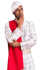 African handsome man wearing tradition sherwani saree clothes bored yawning tired covering mouth with hand. restless and sleepiness.