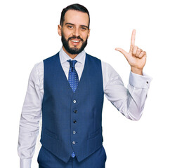 Young man with beard wearing business vest showing and pointing up with fingers number two while smiling confident and happy.