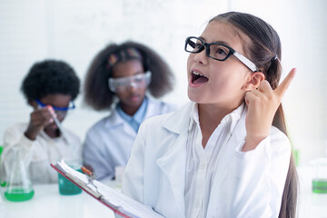 Preteen Caucasian wearing glasses and lab coat showing happy faces for new ideas, her classmates in...