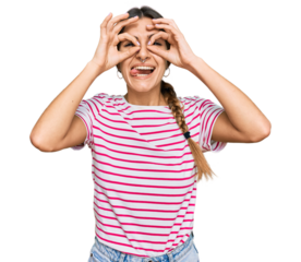 Young hispanic woman wearing casual clothes doing ok gesture like binoculars sticking tongue out, eyes looking through fingers. crazy expression.