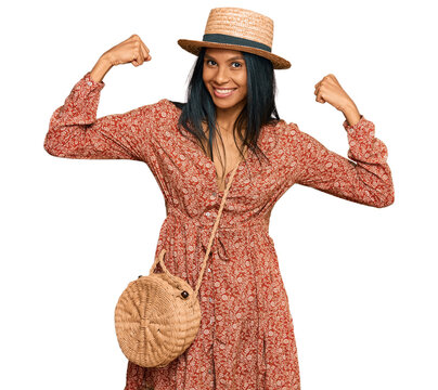 Young african american woman wearing summer hat showing arms muscles smiling proud. fitness concept.