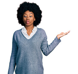 Young african american woman presenting with open palm making fish face with mouth and squinting eyes, crazy and comical.