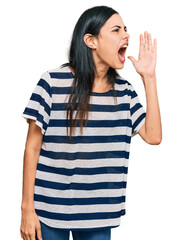 Beautiful young woman wearing casual clothes shouting and screaming loud to side with hand on mouth. communication concept.