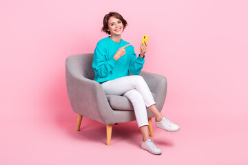 Full length photo of charming lovely girl blogger sitting chair using modern device sumsung iphone isolated on pink color background