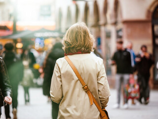 Adult unrecognizable women walking in rainy city streets, focusing on foreground. Crowded road with architecture. Urban spring atmosphere.