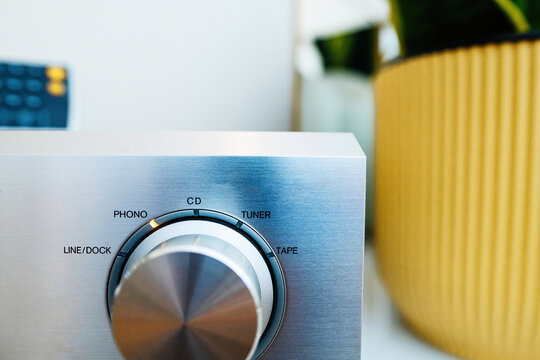 Aluminum front panel of a hi-fi audio device. Close-up of knobs, volume tuner, tape, phono line. Musical and creative setting.