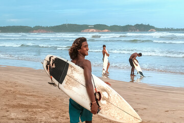 Surfing.Sri Lankans, Indians surfers on the ocean coast with a surfboard, athletic tanned body,...