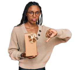 African american woman holding gift with angry face, negative sign showing dislike with thumbs down, rejection concept