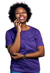 Fototapeta na wymiar African american woman with afro hair wearing casual purple t shirt looking confident at the camera smiling with crossed arms and hand raised on chin. thinking positive.