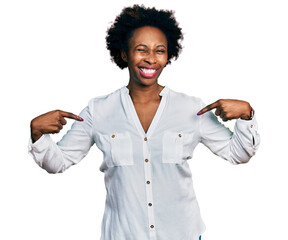 African american woman with afro hair pointing with fingers to herself winking looking at the...