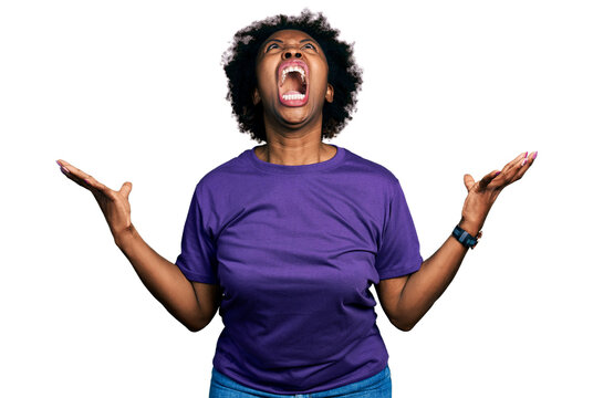 African american woman with afro hair wearing casual purple t shirt crazy and mad shouting and yelling with aggressive expression and arms raised. frustration concept.