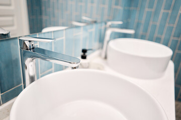 Two sinks in the bathroom sink next to stylish decorations. A beautiful sink with a metal faucet next to an mirror and a shelf with hand towels.. 