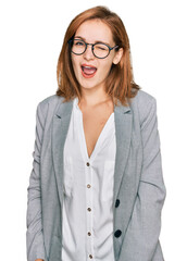 Young caucasian woman wearing business style and glasses winking looking at the camera with sexy expression, cheerful and happy face.