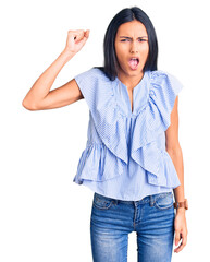 Young beautiful latin girl wearing casual clothes angry and mad raising fist frustrated and furious...