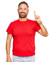 Handsome middle age man wearing casual red tshirt showing and pointing up with finger number one while smiling confident and happy.