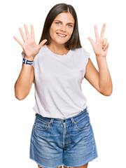 Young caucasian woman wearing casual white tshirt showing and pointing up with fingers number eight while smiling confident and happy.