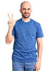 Naklejka premium Young handsome man wearing casual t shirt showing and pointing up with fingers number three while smiling confident and happy.