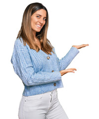 Young woman wearing casual clothes inviting to enter smiling natural with open hand