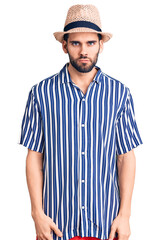 Young handsome man with beard wearing summer hat and striped shirt skeptic and nervous, frowning upset because of problem. negative person.