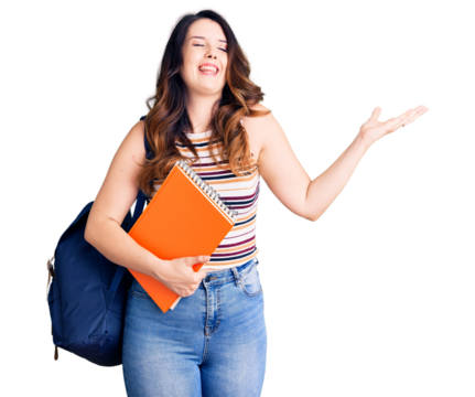 Beautiful young brunette woman wearing student backpack hodling books celebrating victory with happy smile and winner expression with raised hands