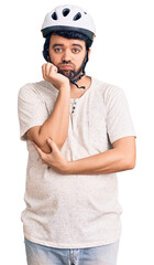 Young hispanic man wearing bike helmet thinking looking tired and bored with depression problems with crossed arms.