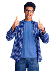 Young african american man wearing casual clothes and glasses success sign doing positive gesture with hand, thumbs up smiling and happy. cheerful expression and winner gesture.