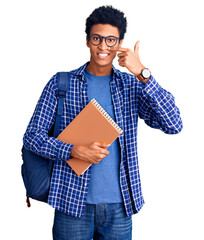 Young african american man wearing student backpack holding book pointing with hand finger to face and nose, smiling cheerful. beauty concept