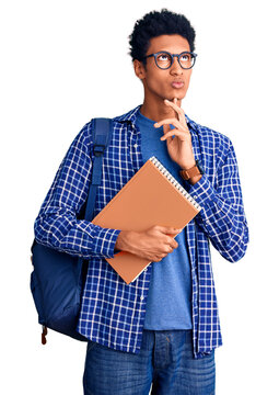 Young african american man wearing student backpack holding book thinking concentrated about doubt with finger on chin and looking up wondering