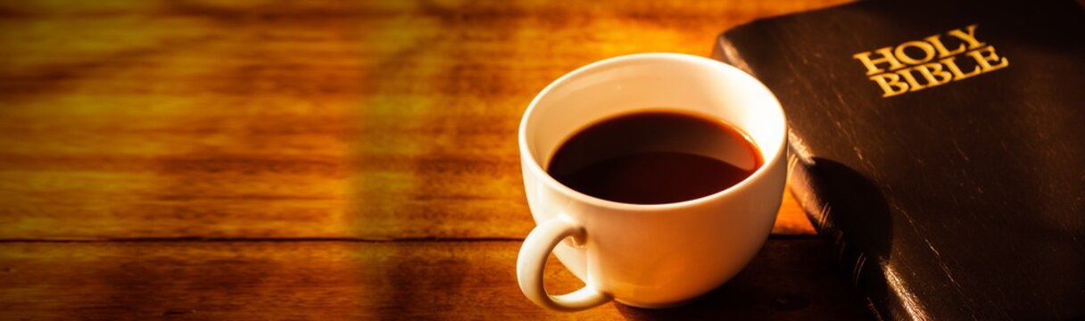 Close up of a cup of coffee and holy bible  on wooden table, Bokeh light effected for web page cover