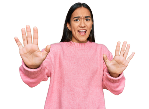 Young asian woman wearing casual winter sweater afraid and terrified with fear expression stop gesture with hands, shouting in shock. panic concept.