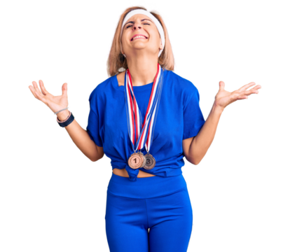 Young blonde woman wearing winner medals celebrating mad and crazy for success with arms raised and closed eyes screaming excited. winner concept - Powered by Adobe