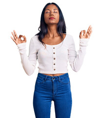 Young indian girl wearing casual clothes relax and smiling with eyes closed doing meditation gesture with fingers. yoga concept.