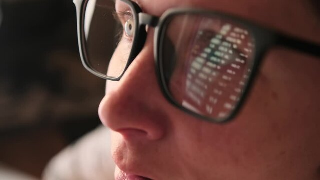 Reflection in eyeglasses of girl of an abstract financial background with online stock market information. Trading report for business concept. Close-up of positive girl studying financial markets.