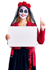 Woman wearing day of the dead costume holding blank empty banner surprised with an idea or question pointing finger with happy face, number one