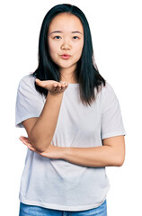 Young chinese woman wearing casual white t shirt looking at the camera blowing a kiss with hand on air being lovely and sexy. love expression.