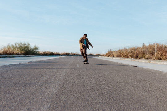 Young bearded skater on asphalt road