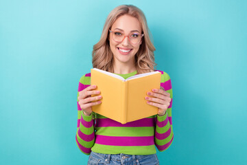 Portrait of satisfied optimistic nice girl with wavy hairdo wear stylish clothes glasses hold book isolated on blue color background