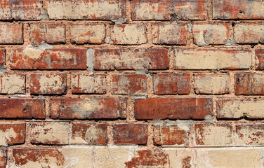 Old red brick wall background partly painted beige stains. Texture close-up. Concept grunge and creative.